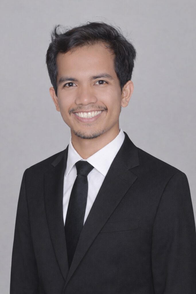 A professional headshot of a man in a black suit, white shirt, and black tie, smiling at the camera. This image could be representative of individuals seeking jobs in Japan, particularly from Indonesia or other overseas locations. While it doesn't contain specific job role details, it embodies the professional image needed for securing positions in Japan, relevant for expats looking for work and a secure life for their families via platforms like Daijob. It could be part of a series on securing a future for children or parenting in Japan as a foreigner.
